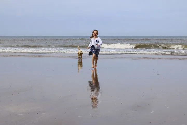 girl running with dog on beach